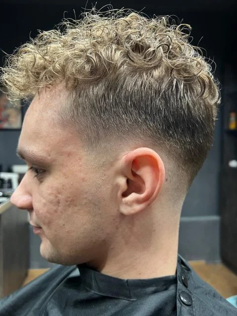 Męska fryzura z naturalnymi lokami na górze i precyzyjnym cieniowaniem typu Low Fade na bokach - Barber Krosno