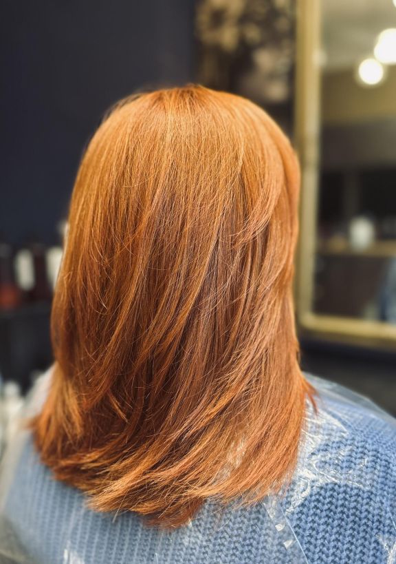 Damskie strzyżenie cieniowane średniej długości z koloryzacją w odcieniu naturalnej miedzi. Fryzura zwiększająca objętość. Salon fryzjerski Jawor